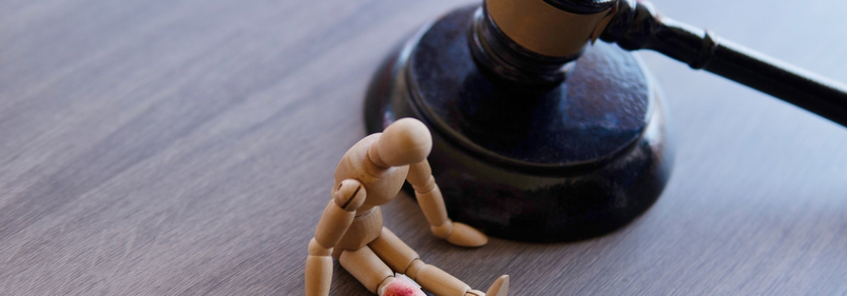 Bandage wrap with blood stain, wooden doll and judge gavel. Personal injury law concept.