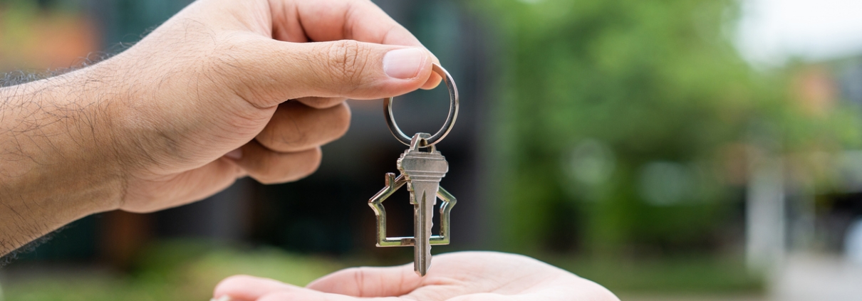 Woman buying or rent new home she holding key front of new house. Surprise happy young asian woman giving house key and smile to rent or purchase apartment home. Moving relocation concept.
