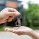 Woman buying or rent new home she holding key front of new house. Surprise happy young asian woman giving house key and smile to rent or purchase apartment home. Moving relocation concept.