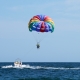 tourists fly on a multicolored parachute tied to a boat