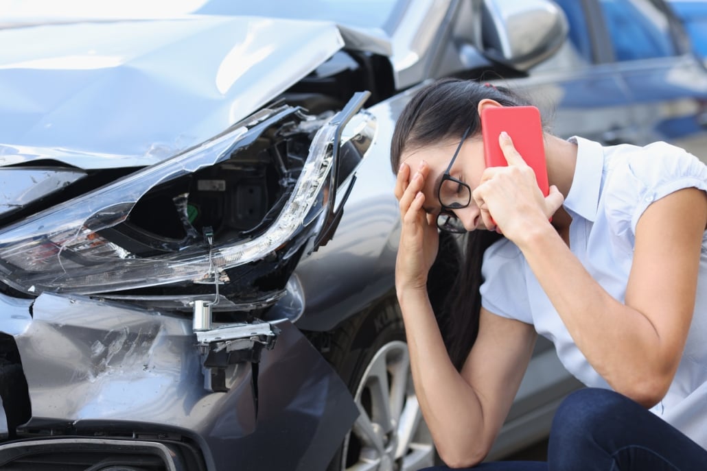 Sad woman talking on cell phone near wrecked car. Female driver concept