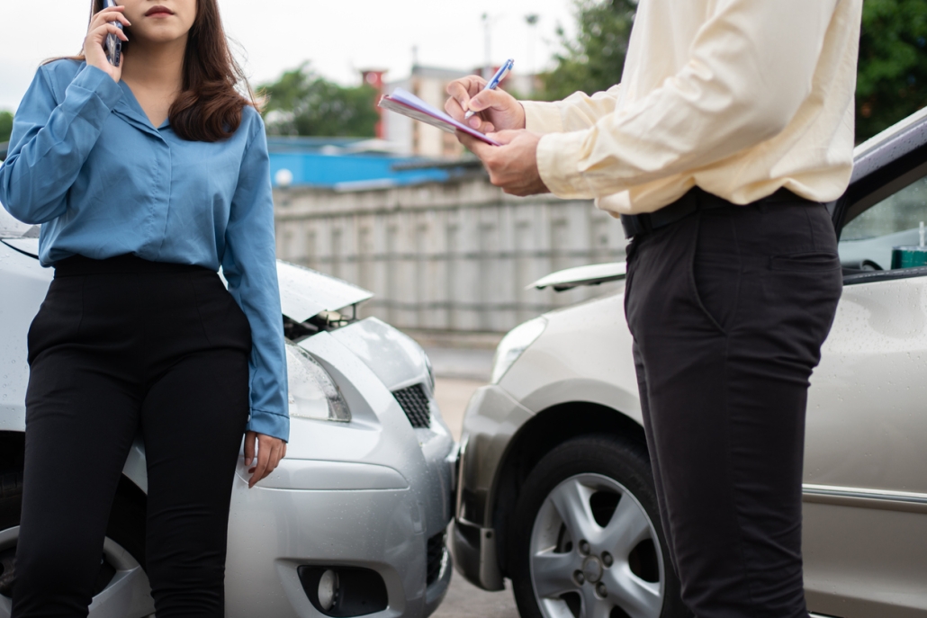 Asian women driver Talk to Insurance Agent for examining damaged car and customer checking on report claim form after an accident. Concept of insurance and car traffic accidents.