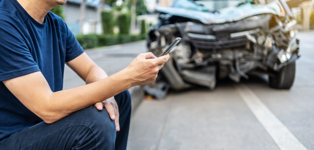 Man calling with phone to his insurance agent after traffic accident with a background of the crashed car, Car insurance an non-life insurance concept.