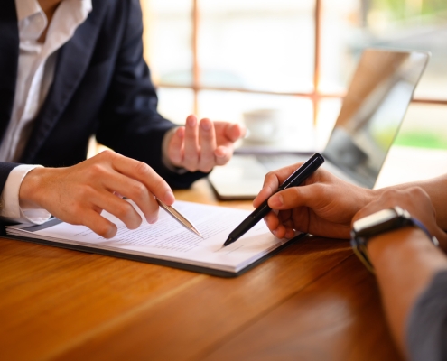 Closeup lawyer or insurance agent pointing at contract showing male client where to signature sign.