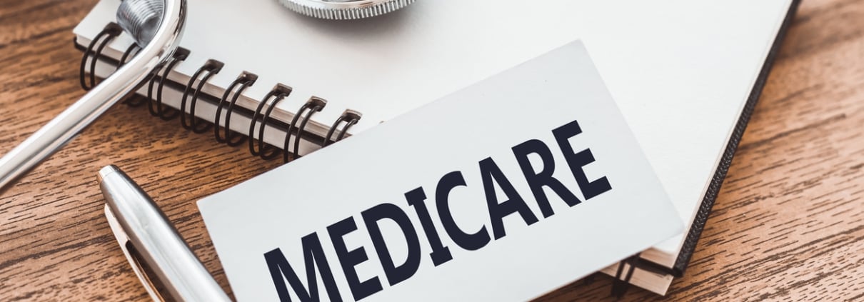 MEDICARE - text on card on wooden table with stethoscope and notepad for medical records.