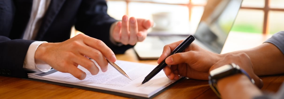 Closeup lawyer or insurance agent pointing at contract showing male client where to signature sign.